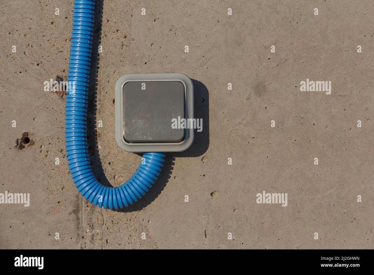 Industrielle elektrische Schalter mit geschütztem Kabel an einer Betonwand. Industriebeleuchtung. Stockfoto