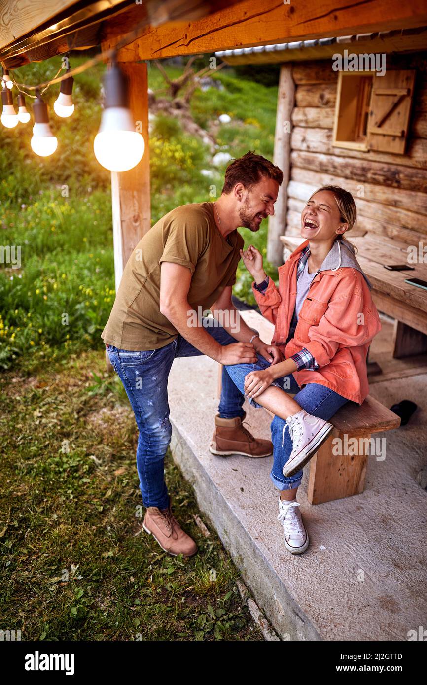 Junge attraktive fröhliche Paar brach in Lachen vor der Holzhütte. Wunderbare Momente. Urlaub, Urlaub, Zweisamkeit Konzept. Stockfoto