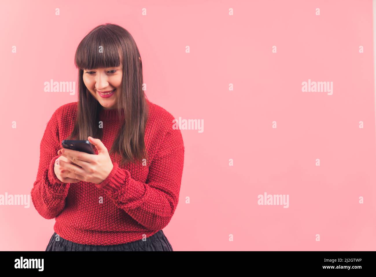 Nur positive Vibes. Glücklich Influencer Mädchen mit ihrem Smartphone über rosa Hintergrund. Social-Media-Konzept. Hochwertige Fotos Stockfoto