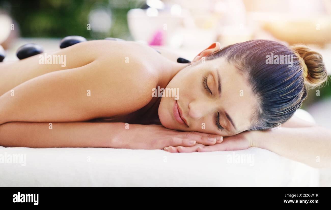 Ich kann nicht anders, als in einem so magischen Zustand davonzutreiben. Aufnahme einer jungen Frau, die in einem Spa eine Hot-Stone-Massage bekommt. Stockfoto