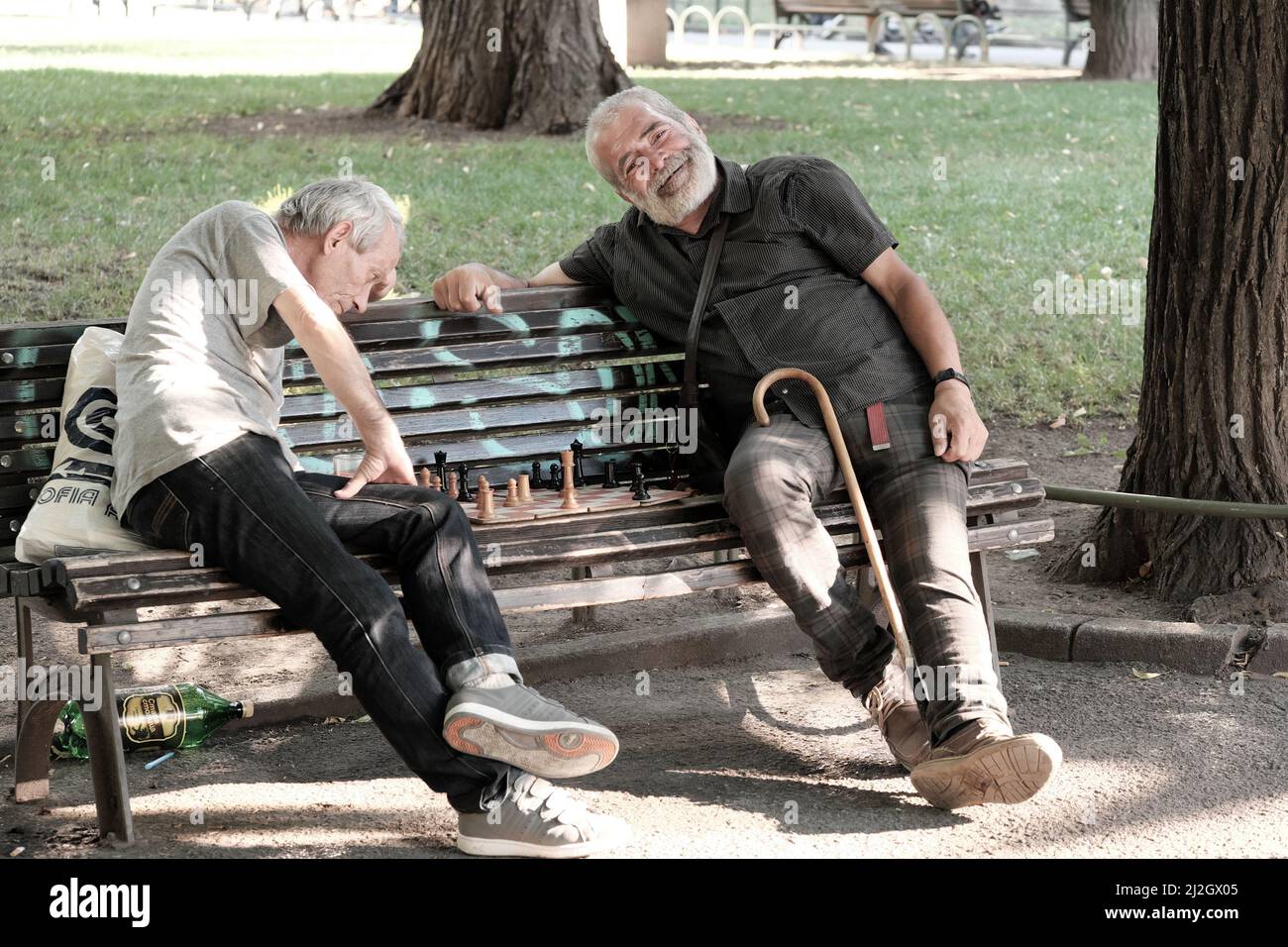 SOFIA, BULGARIEN - 02. AUGUST 2017: Zwei Männer mittleren Alters sitzen auf einer Bank und spielen ein Schachspiel in einem Stadtgarten in der Innenstadt von Sofia Stockfoto