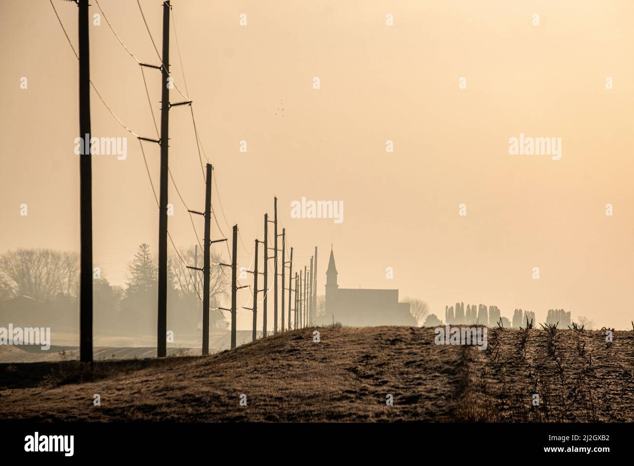 Telefonmasten und ein Kirchturm neben einem Feld im ländlichen amerikanischen Mittleren Westen Stockfoto