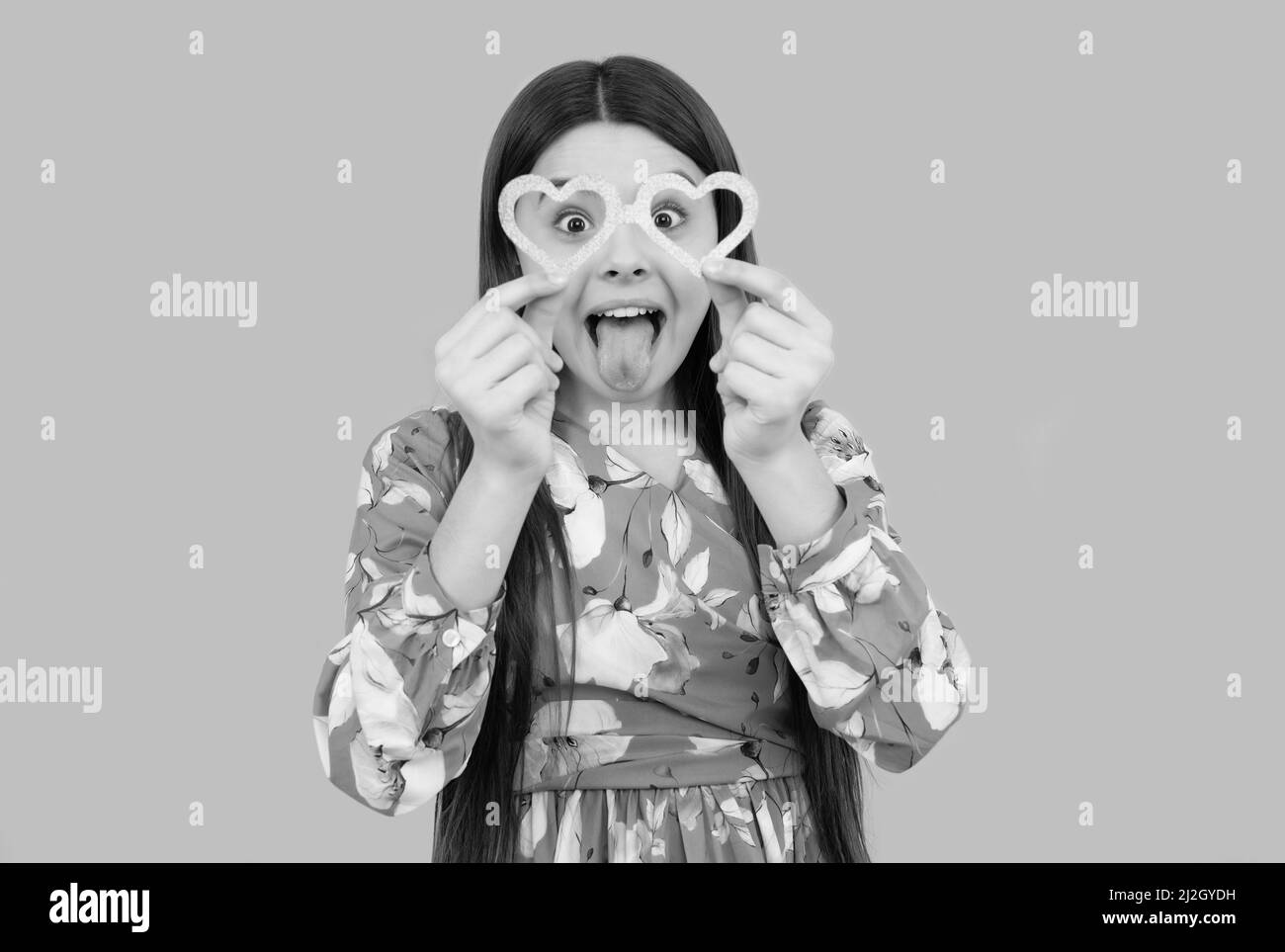 Das ist einfach dumm. Albernes Mädchen ragt die Zunge in einer herzförmigen Brille heraus. Valentinstag Stockfoto