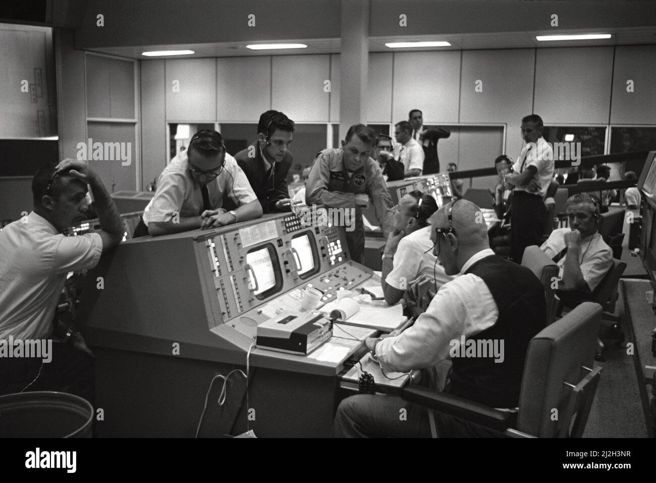 Ansicht der Flight Directors Konsole im Mission Control Center (MCC), Houston, Texas, während des Gemini 5-Flugs. An der Konsole sitzen Eugene F. Kranz (Vordergrund) und Dr. Christopher C. Kraft Jr. (Hintergrund). Vor der Konsole stehen Dr. Charles Berry (links), ein nicht identifizierter Mann im Zentrum und Astronaut Elliot M. See. Stockfoto