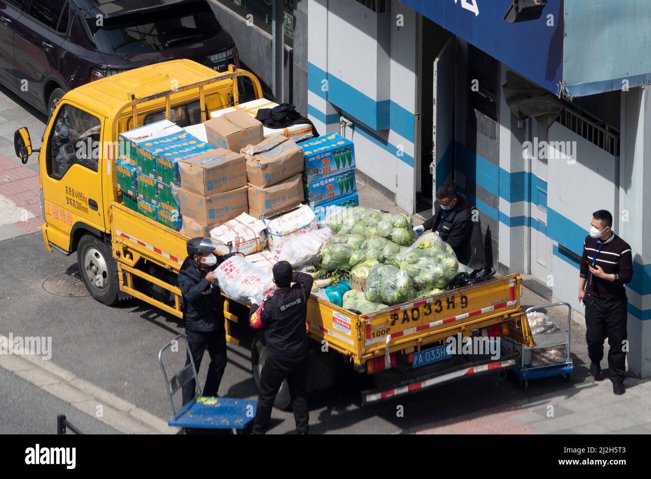 SHANGHAI, CHINA - 2. APRIL 2022 - am 2. April 2022 laden Arbeiter Gemüse, Lebensmittel und andere Notwendigkeiten in einen gelben Lastwagen in Shanghai, China. Stockfoto