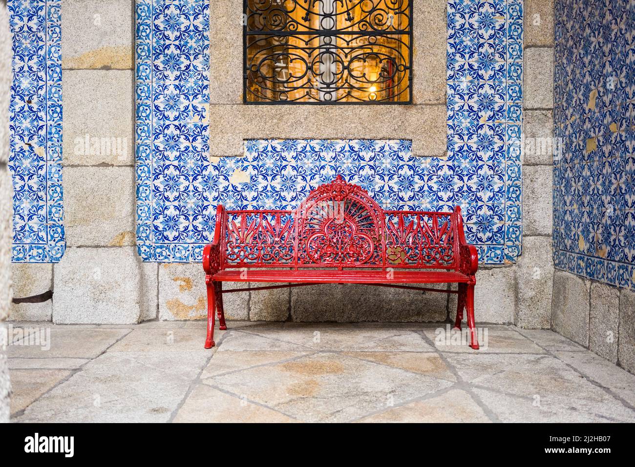 Portugal, Porto, Rote Bank vor der mit Azulejos bedeckten Wand Stockfoto