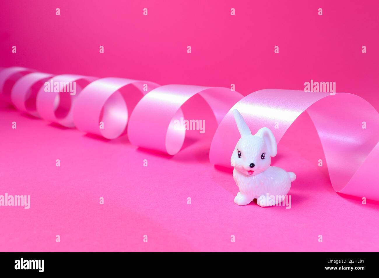 Kleines weißes Kaninchen und rosa Band Hintergrund Stockfoto