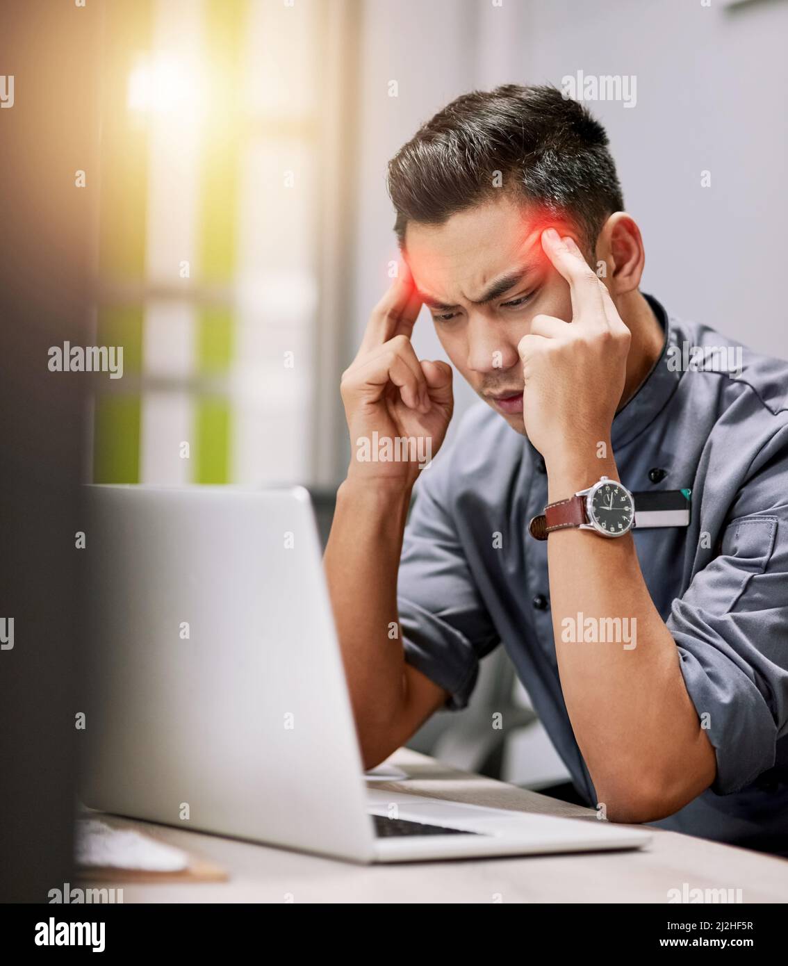 Der Druck kommt zu ihm. Aufnahme eines jungen Mannes, der bei der Arbeit an seinem Laptop Kopfschmerzen hatte. Stockfoto