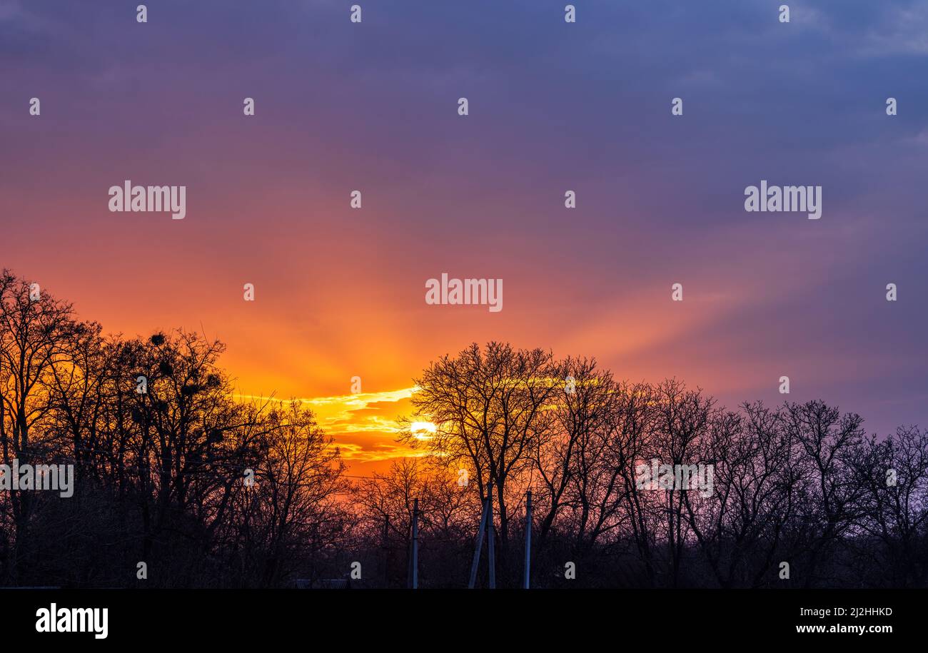 Die Sonne strahlt am dunklen Himmel bei Sonnenuntergang. Stockfoto