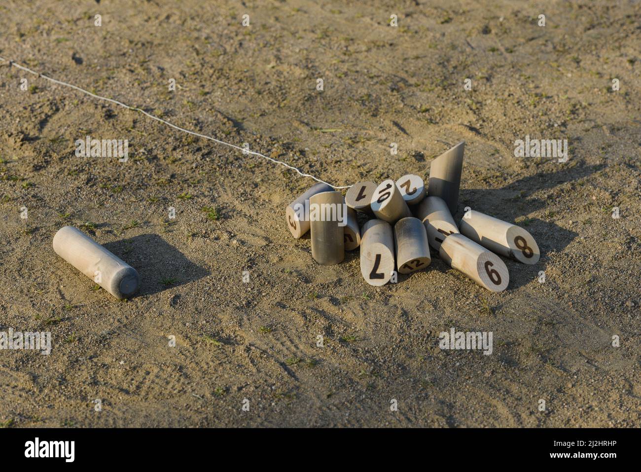 Molkky-Kegeln breiteten sich auf dem Sandboden einer Bowlingbahn aus, nachdem der Stock daneben geworfen wurde Stockfoto