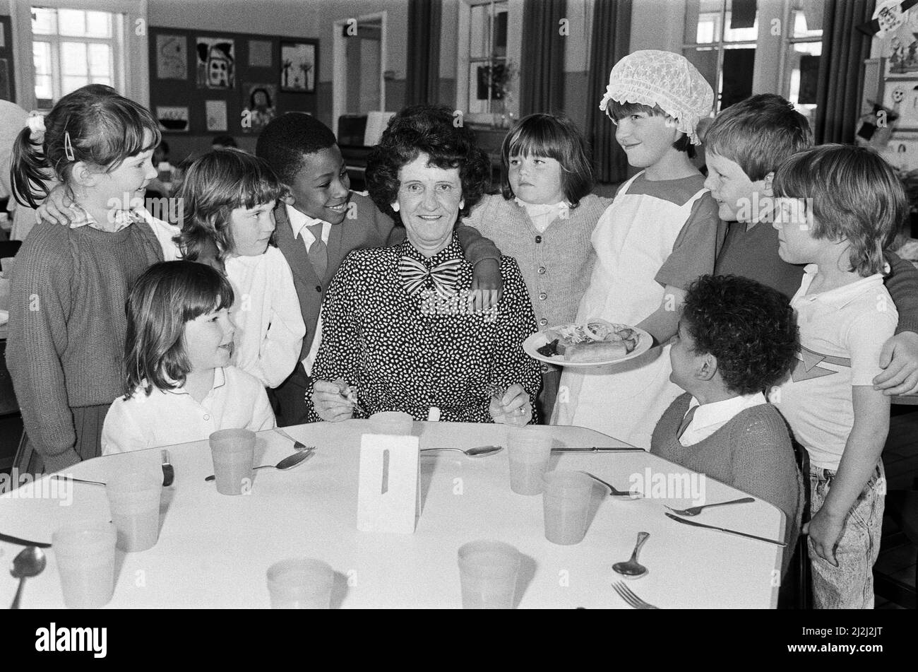 Stilvolles Essen... die pensionierte Dinner-Dame Mrs. Edna Maloney bekommt die VIP-Behandlung während ihrer letzten Mittagspause in der Berry Brow Infant's and Nursery School. Die Schülerin Sarah Bedford hat Mrs. Maloney mit Schürze und Mütze aufgesetzt, um ihr einen Eindruck vom Leben auf der anderen Seite der Servierluke zu geben. Es war ein Festtag für Frau Maloney aus Lepton, die ihren 65.. Geburtstag auch mit einer speziellen Disco-Party in der Schule feierte. Die Kinder überreichten ihr ein Aquarell von Castle Hill und einen Blumenstrauß. Sie erhielt auch eine keramische jardiniere von Mitarbeitern und Freunden. 27. Mai 1988. Stockfoto