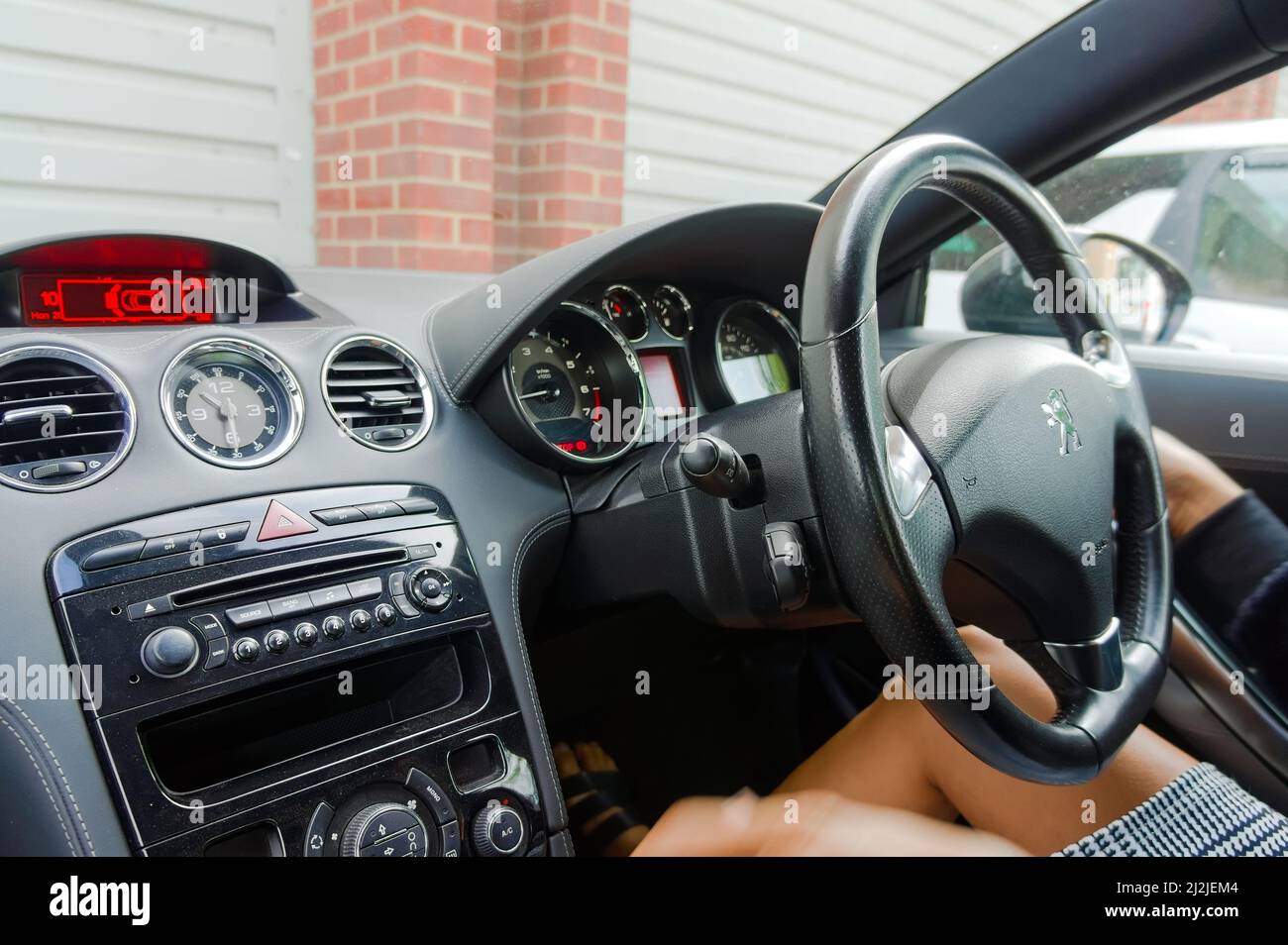 Innenraum des Peugeot-Sportwagens mit einer Frau am Steuer, aber ohne Gesichtsausdruck. Stockfoto