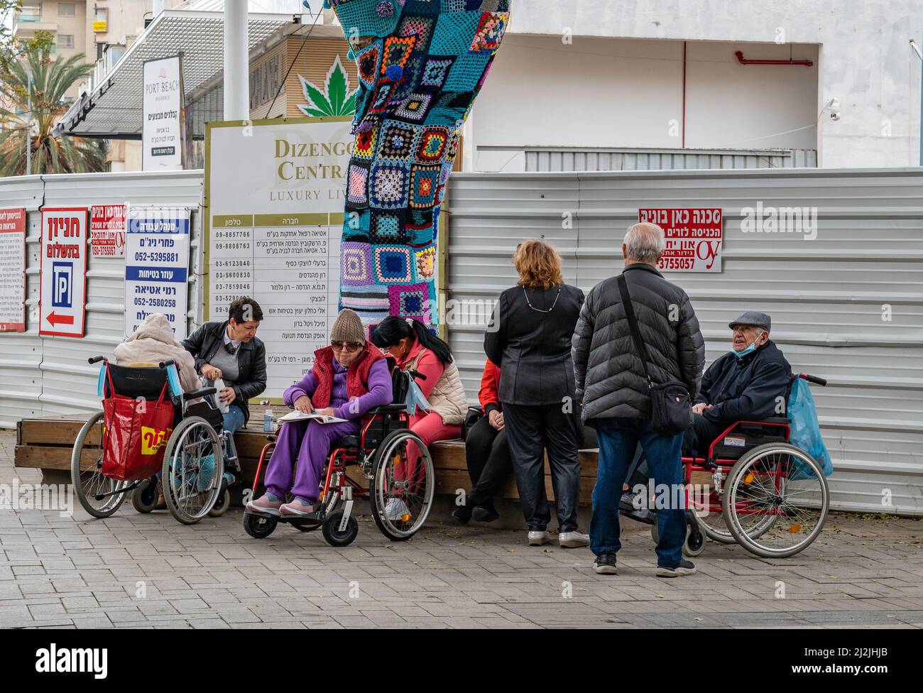 Netanya, Israel - 7. Februar 2022: Eine Gruppe älterer Menschen in Rollstühlen, die mit Sozialarbeitern im Park spazieren gehen. Nahaufnahme. Stockfoto