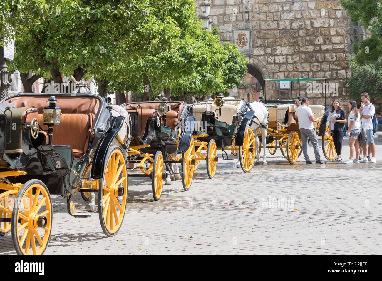 Sevilla, Spanien - 10. Mai 2018: Serie von Pferdekutschen, mit gelben Rädern, erwartet Touristen in Sevilla Stockfoto