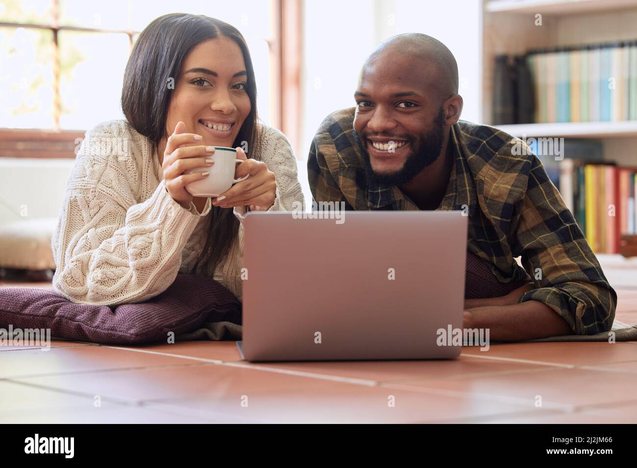 Wilde Pferde konnten mich nicht wegschleppen. Aufnahme eines jungen Paares, das zu Hause eine gute Zeit miteinander verbringt, während es sich einen Film auf einem Laptop ansieht. Stockfoto