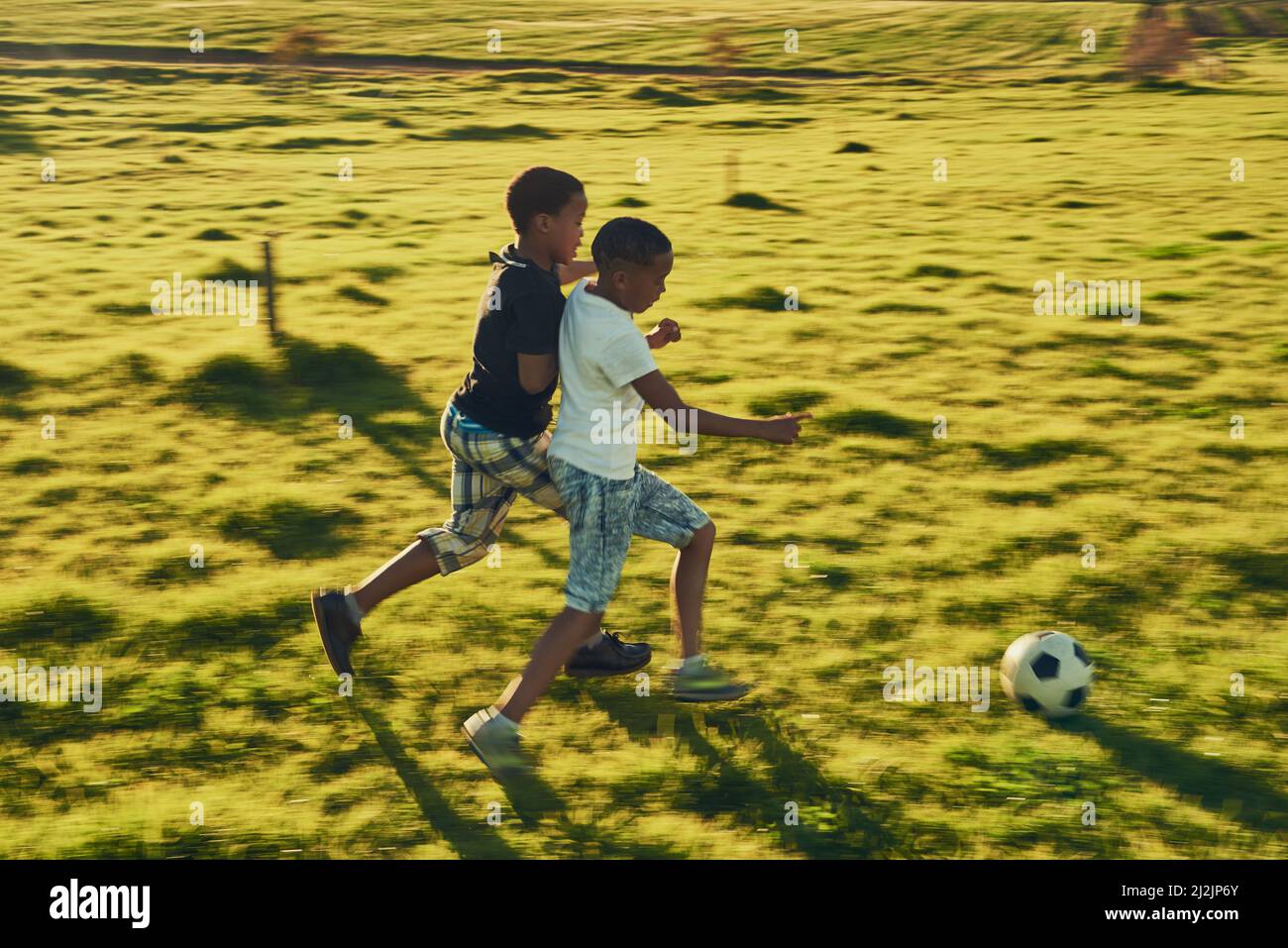Fußball-Spaß mit einem Freund. Aufnahme von zwei Kindern, die draußen auf einem Feld zusammen Fußball spielen. Stockfoto