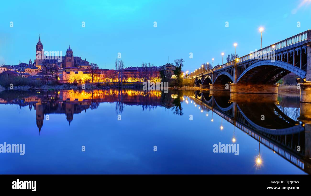 Nächtliches Stadtbild der Stadt Salamanca und des Flusses Tormes mit seiner Eisenbrücke. Stockfoto