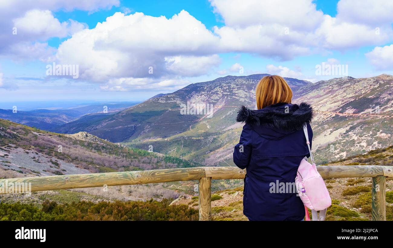 Frau, die die bergige Landschaft von einem Aussichtspunkt auf der Spitze der Hügel betrachtet. Stockfoto