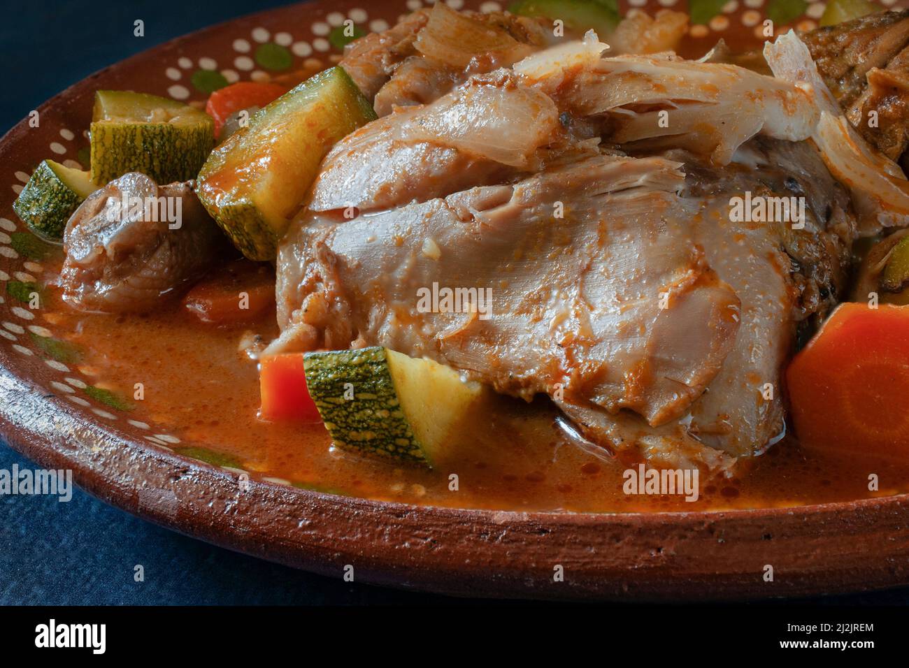 Huhn mit Gemüse und Tomatensoße in einer mexikanischen Tonplatte. Mexicam Food-Konzept. Seitenansicht Makrofotografie Stockfoto