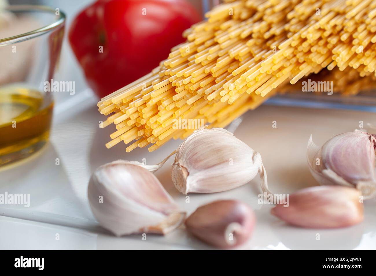 Makrofotografie, rohe, ungekochte Spaghetti mit Zutaten auf einem Tisch, fertig zum Kochen. Stockfoto