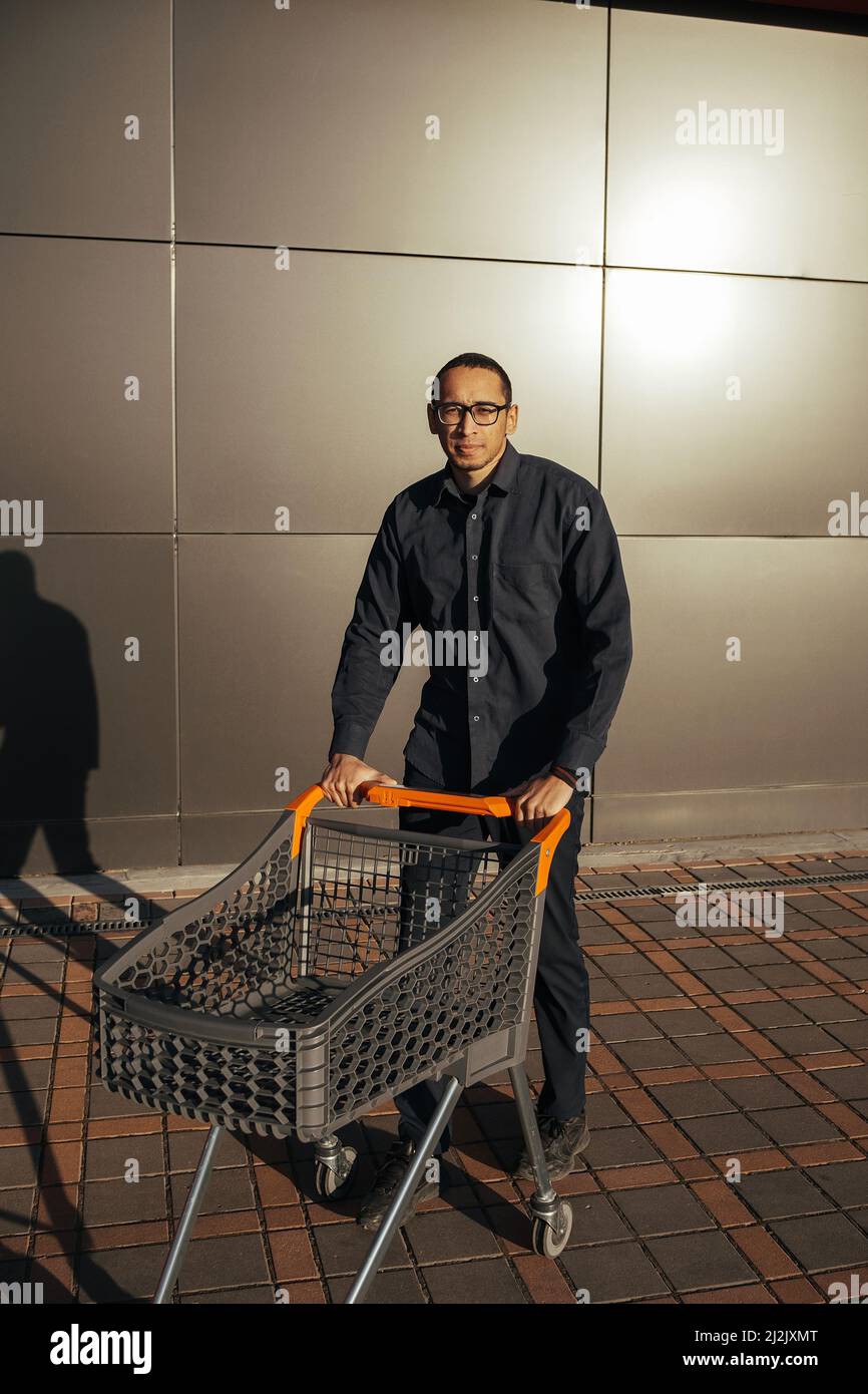 afro-Shopping mit einem Einkaufswagen, der Typ ist in der Nähe der Mall einkaufen Stockfoto
