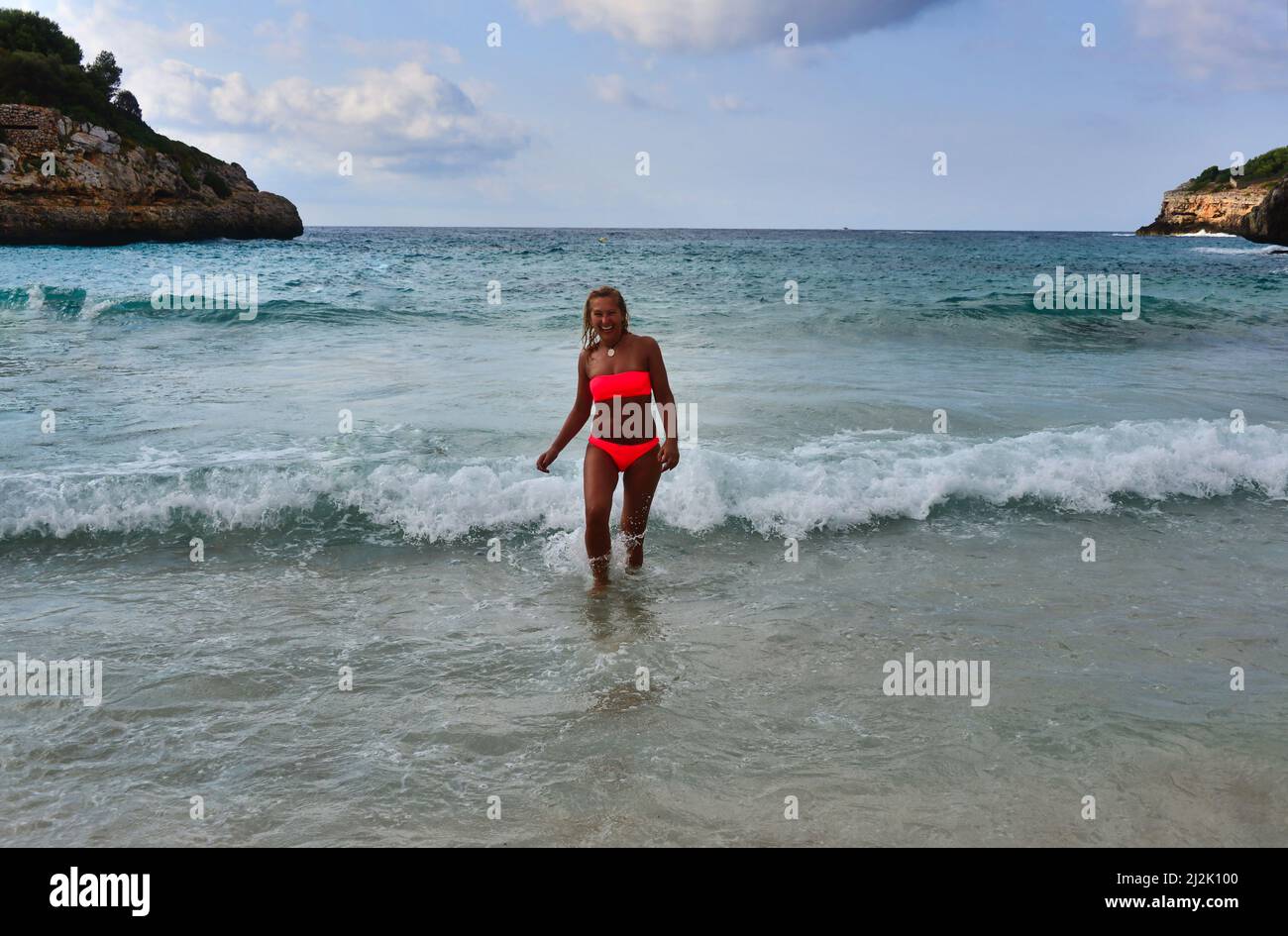 Lächelnde Frau in einem Bandeau-Bikini, die aus dem Meer läuft, Porto Cristo, Mallorca, Spanien Stockfoto