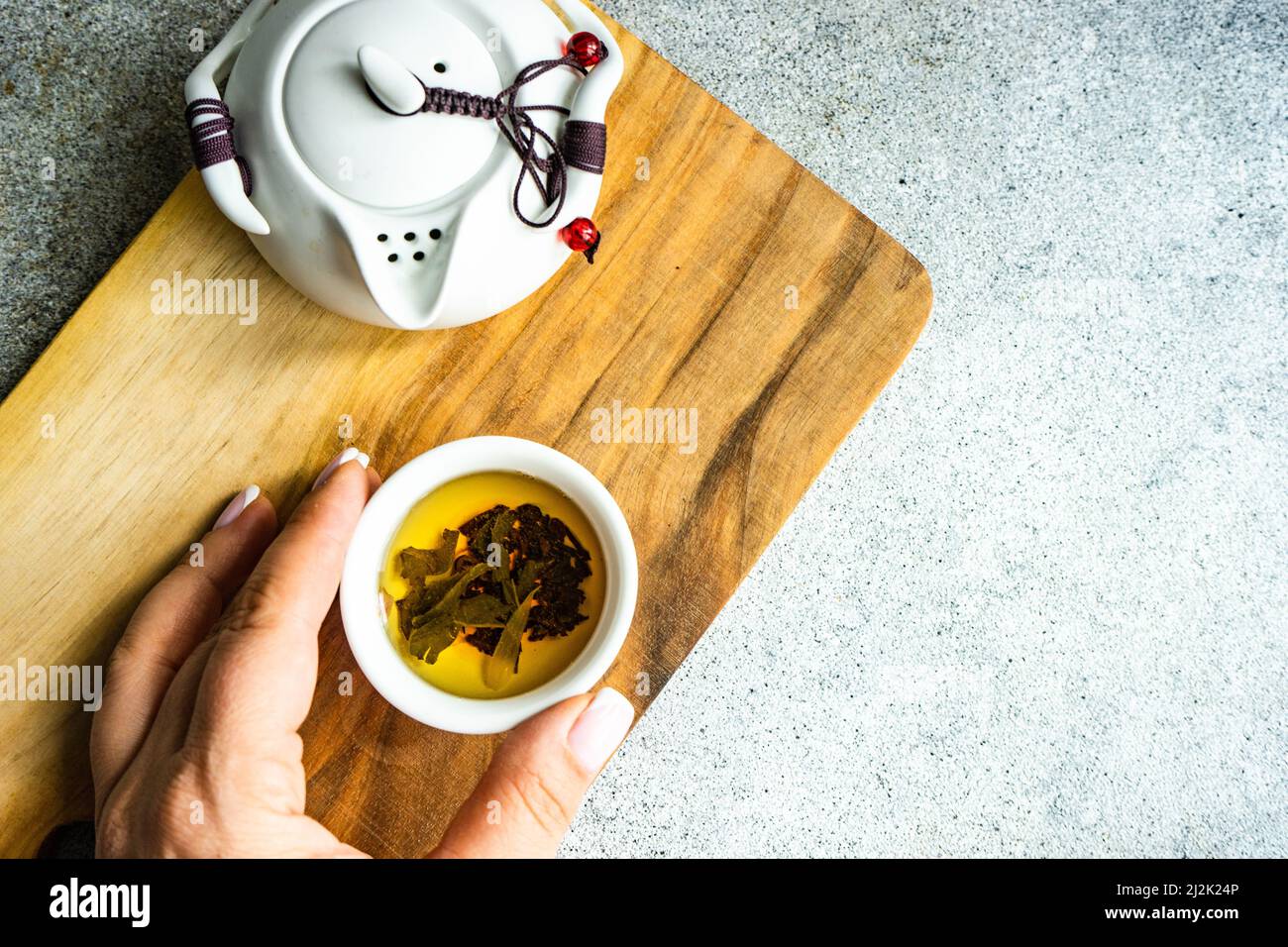 Frau, die nach einer Tasse grünen Tee greift Stockfoto