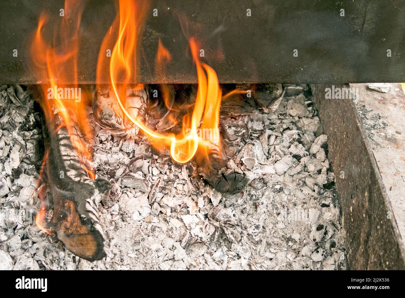 Smokehouse für warmes Rauchen am Feuer. Eine Metallbox mit einem Produkt auf einem köcheln Feuer. Stockfoto