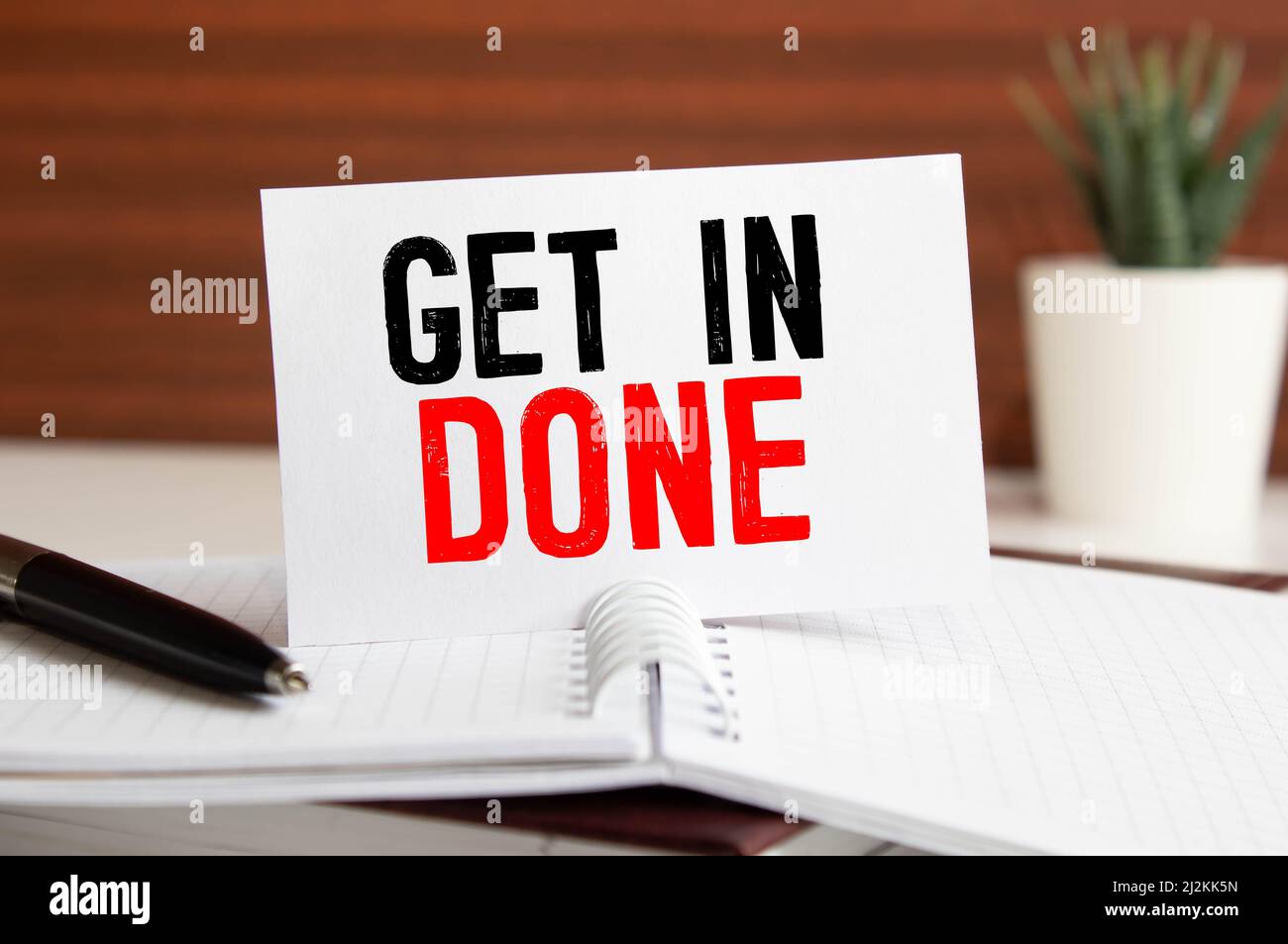 Die Phase Get More Done. In rotem Text auf einer gelben Haftnotiz, die an einen Wandkalender angebracht ist. Stockfoto