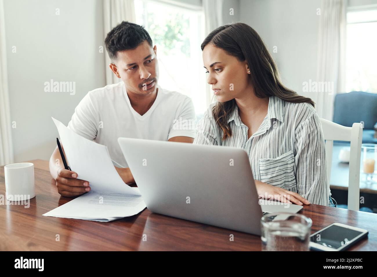 Es ist ein Zahlenspiel. Eine kleine Aufnahme eines jungen Paares, das einen Laptop für sein Haushaltsbudget im Wohnzimmer zu Hause verwendet. Stockfoto