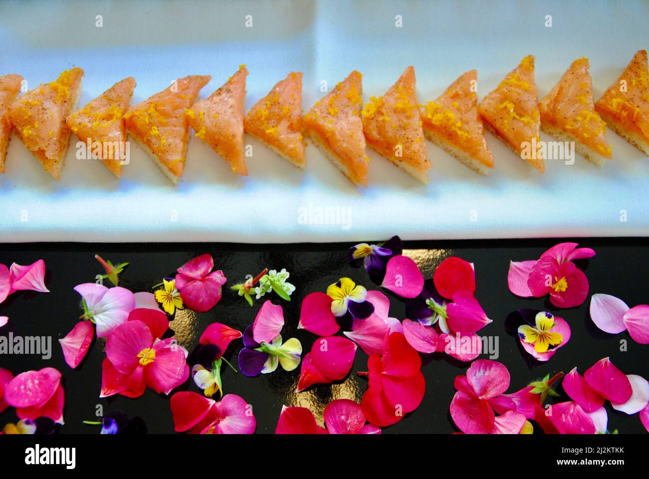 Canapés mit geräuchertem Lachs auf Tablett, verziert mit essbaren Blumen Stockfoto