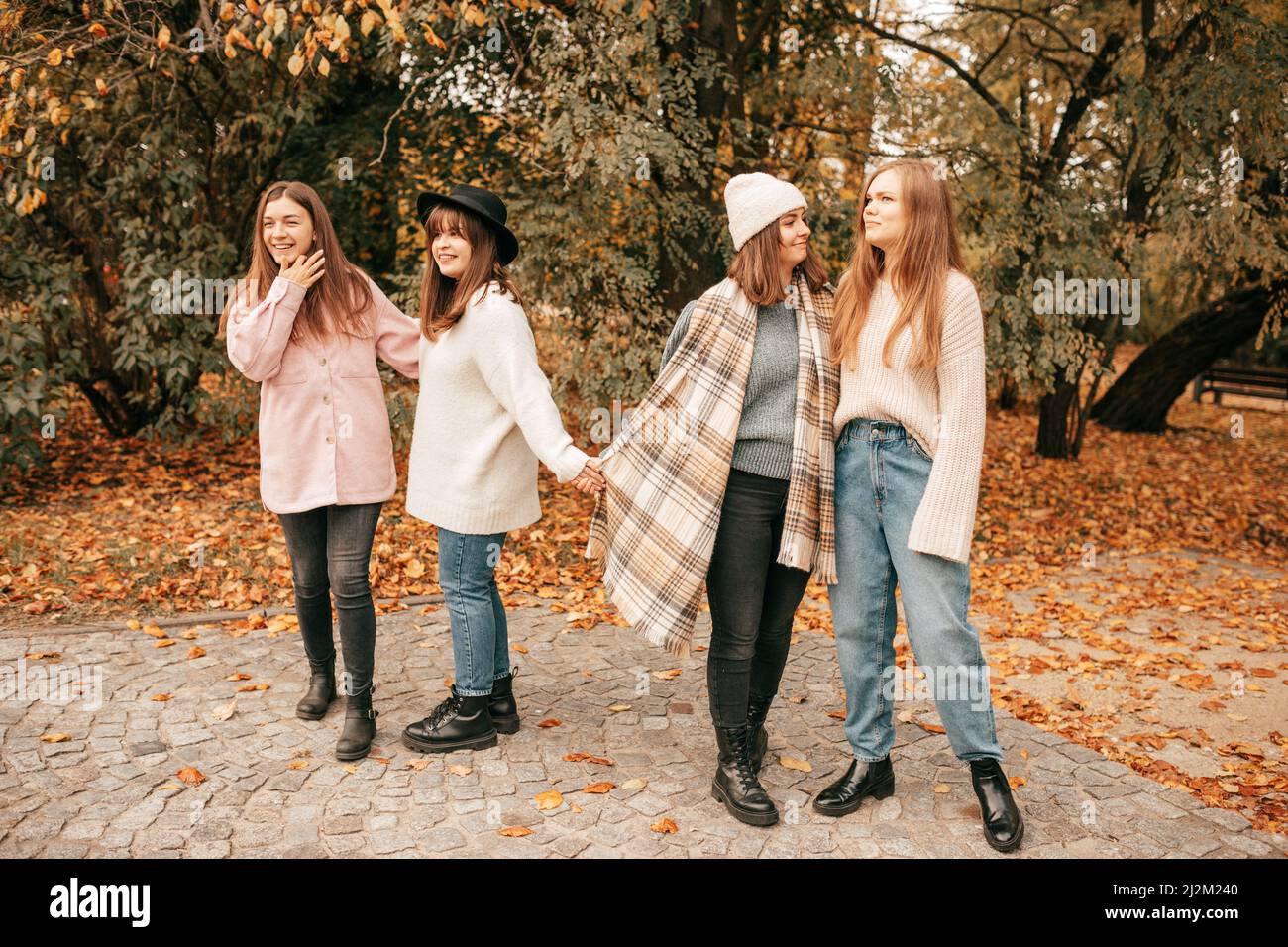 Vier enge Freundinnen treffen sich nach der Universität, verbringen Zeit miteinander und halten sich im Herbstgoldpark die Hände Stockfoto
