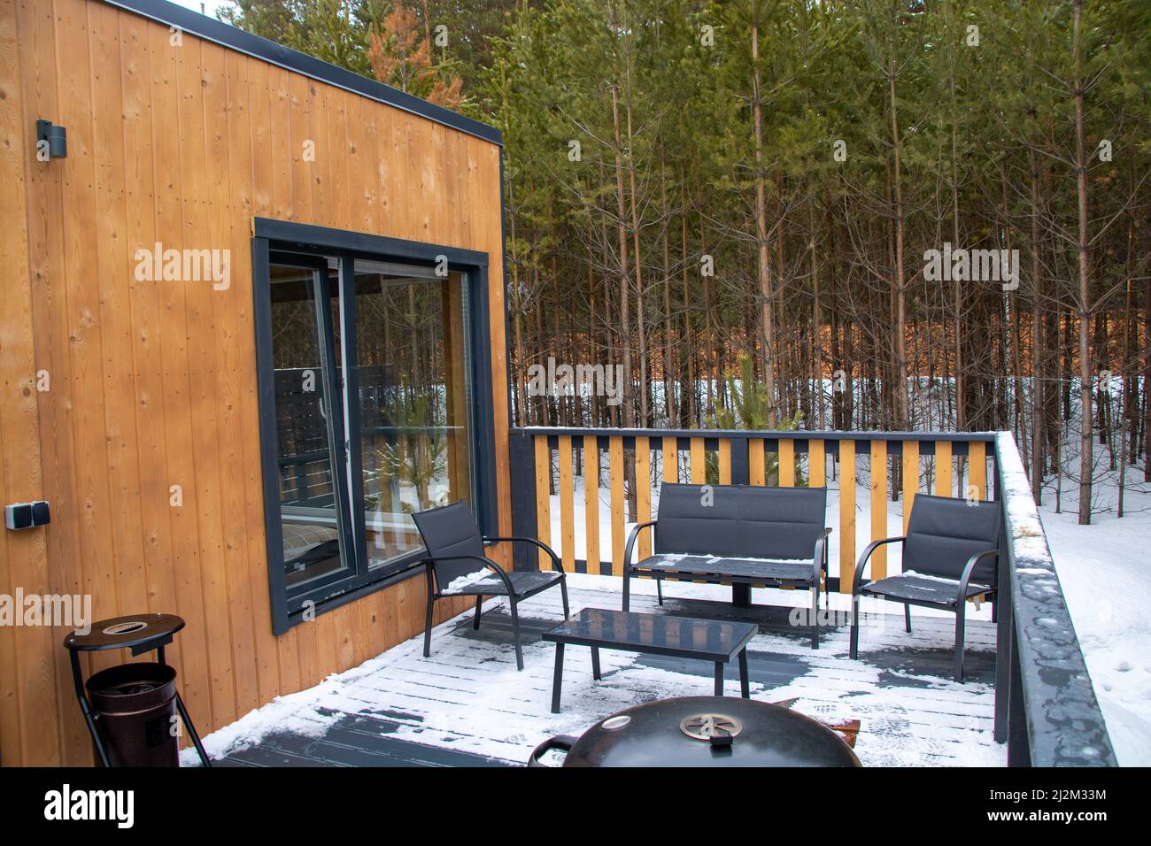 skandinavisches Haus mit Panoramafenster und Terrasse im Winterwald Stockfoto