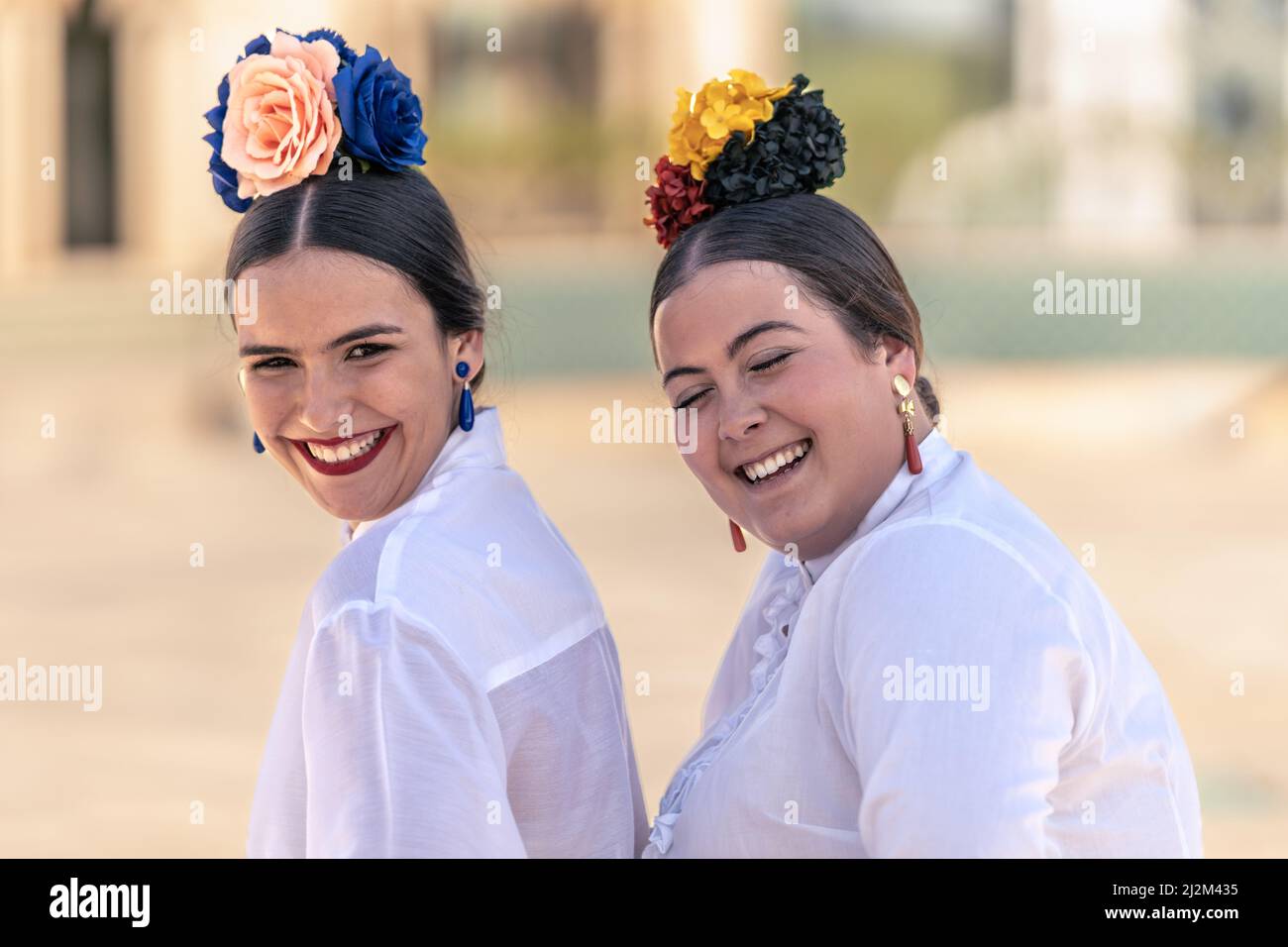 Portrait von zwei Teenagern in Flamenco-Kleidern, die laut lachen Stockfoto