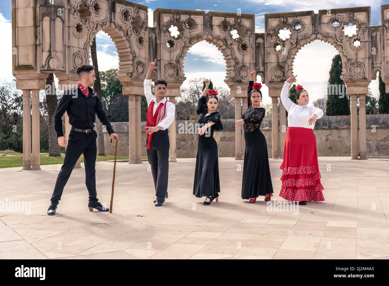 Auf einem Platz vor einigen Zierbögen unterweist ein Flamenco-Meister seine Lehrlinge Stockfoto