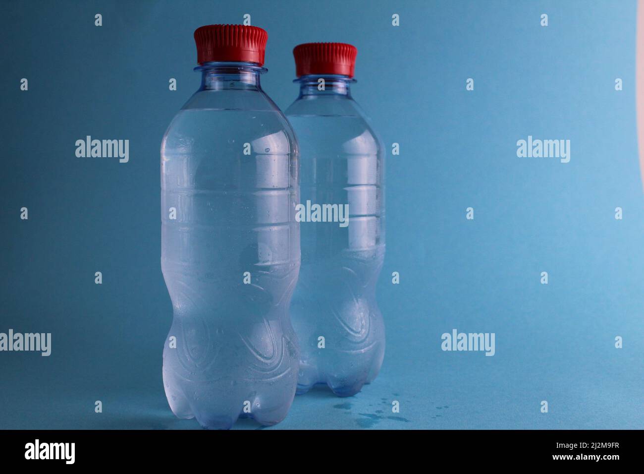 Trinken mineraliertes Wasser in Plastikflaschen auf blauem Hintergrund mit Platz für Text und mit Copypispe. Reines Wasser. Kalte alkoholfreie Getränke. Auffrischung Stockfoto