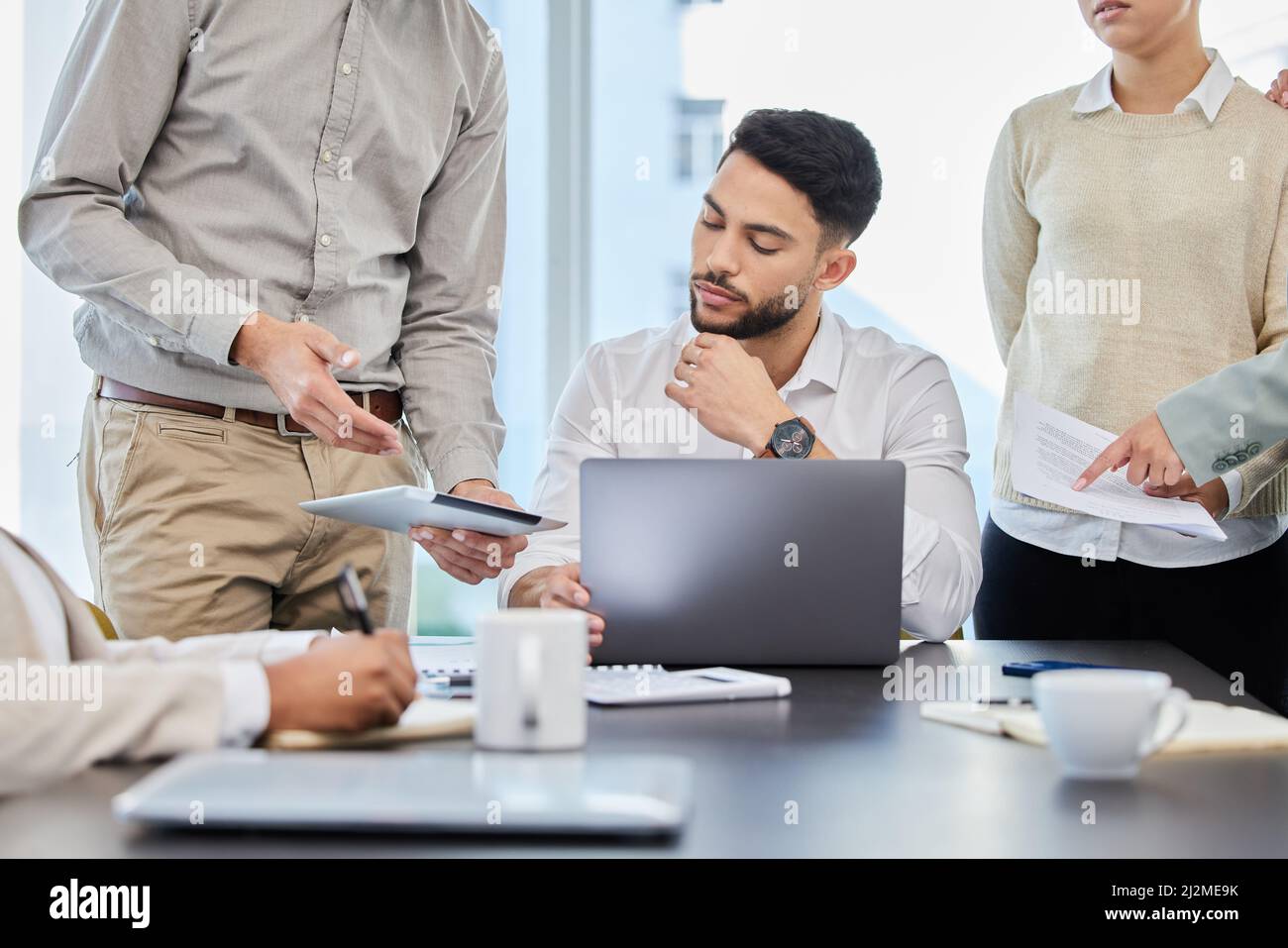 Jeder Plan muss zuerst von ihm genehmigt werden. Aufnahme eines jungen Geschäftsmannes, der in einem Büro mit seinen Kollegen diskutiert. Stockfoto