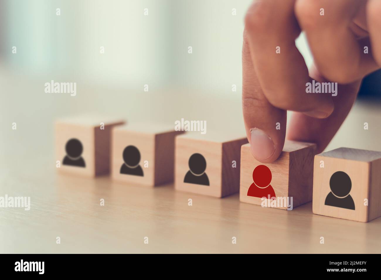 Personalmanagement, Rekrutierung und Zielkundengeschäft. Die Hand des Mannes setzt eine rote Person aus Holzwürfel, die auf der Menge mit Schwarz steht Stockfoto