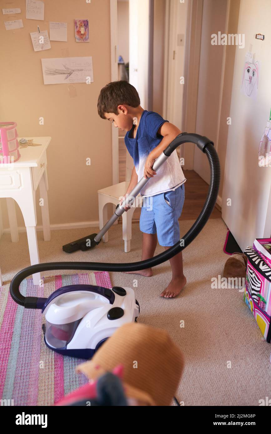 Aufräumzeit. Aufnahme eines kleinen Jungen, der zu Hause sein Schlafzimmer saugt. Stockfoto