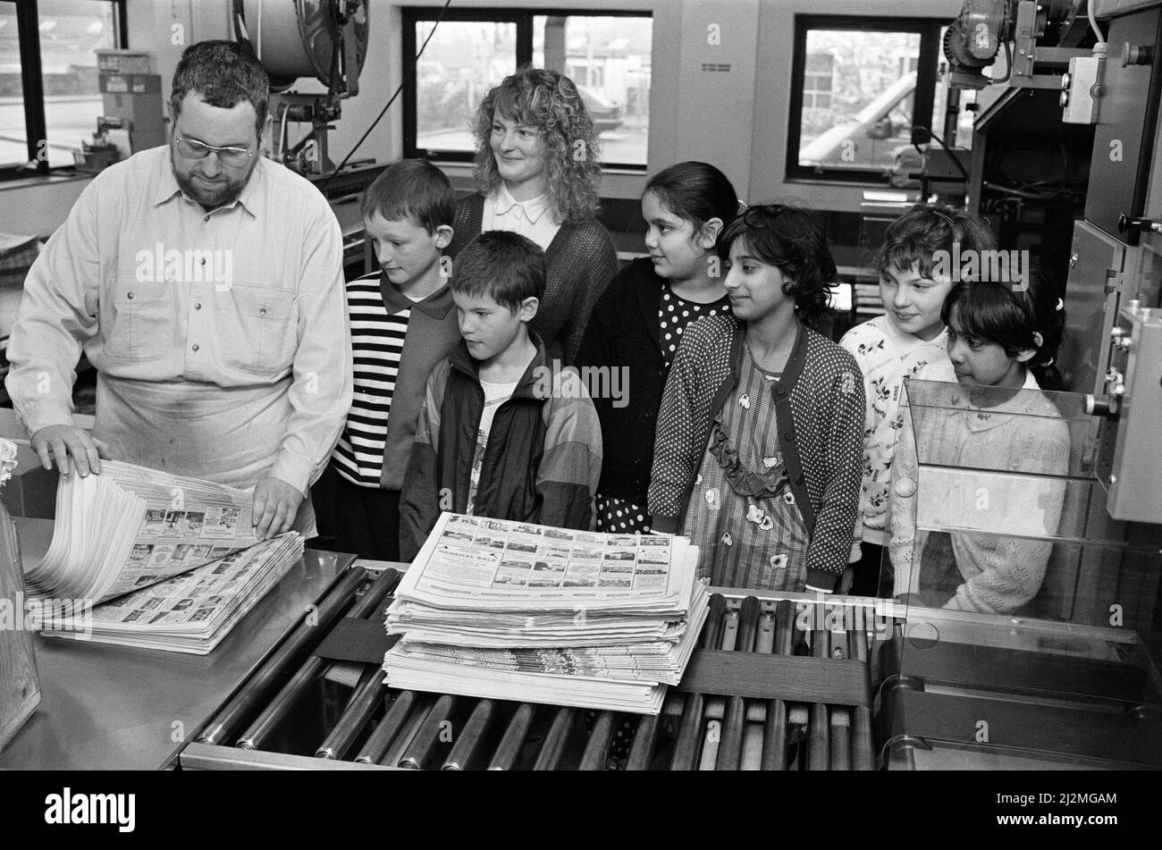 Countdown des Prüfers - Schüler der Moldgreen Junior School, zusammen mit der Lehrerin Susan Ingham, beobachten Martin Flynn, wie er in der Verlagsabteilung der Zeitung Kopien auszählt. Etwa 30 Kinder besuchten die Examiner-Pressehalle in Aspley, um zu sehen, wie das Papier hergestellt wird. Sie sahen sich das Video auch an, als sie Schlagzeilen machten, und hörten einen Vortrag von Paul Clark, einem leitenden Angestellten für Öffentlichkeitsarbeit. 31.. Januar 1991. Stockfoto
