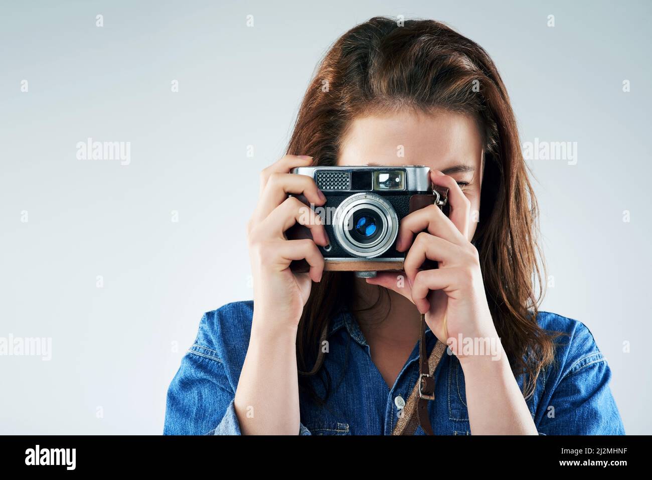 Retro ist der Weg zu gehen. Studioportrait einer jungen Frau mit einer Vintage-Kamera vor grauem Hintergrund. Stockfoto Retro ist der Weg zu gehen. Studioportrait einer jungen Frau mit einer Vintage-Kamera vor grauem Hintergrund. Stockfoto