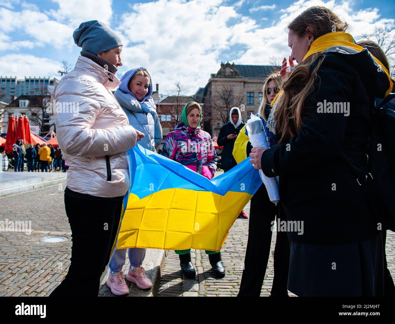Den Haag, Niederlande. 02. April 2022. Eine Gruppe ukrainischer Frauen sah während der Demonstration eine ukrainische Flagge entfalten. Vor dem Repräsentantenhaus der Niederlande wurde eine ukrainische Kunstinstallation aufgestellt, um die Aufmerksamkeit der niederländischen Behörden und der Bevölkerung auf die Tötungen von Zivilisten und insbesondere von Kindern während des Krieges in der Ukraine zu lenken. Kredit: SOPA Images Limited/Alamy Live Nachrichten Stockfoto
