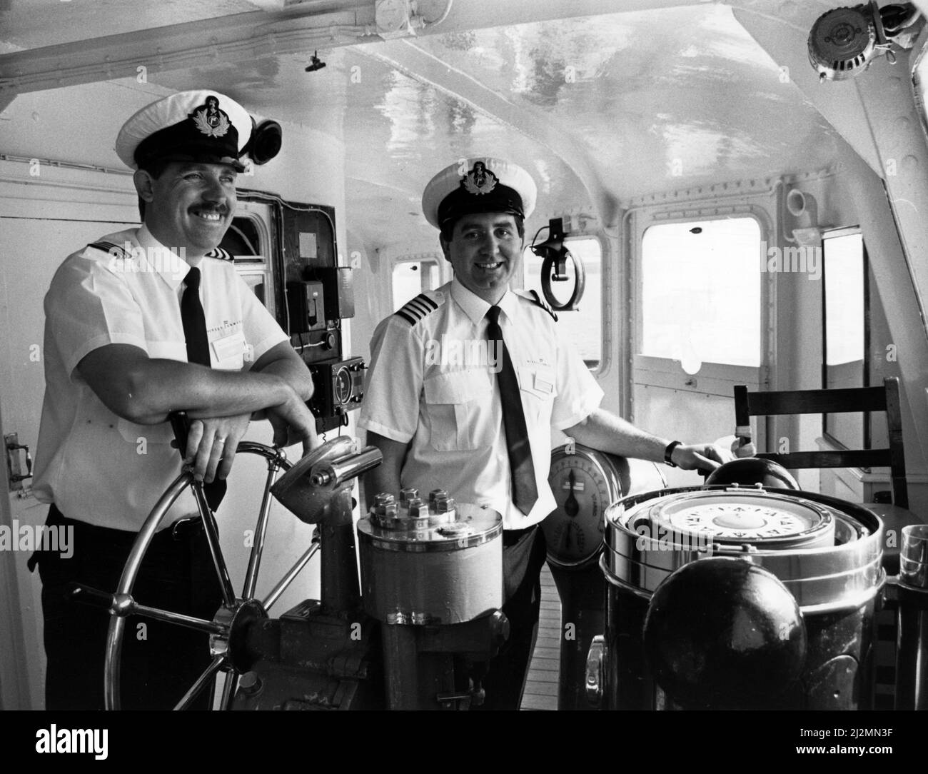 MV Royal Iris, Captain Tony Murphy (rechts) und First Mate Robbie Quinn steuern die Iris aus, um die QE2 zu treffen. 24.. Juli 1990. Die MV Royal Iris ist eine dieselelektrische Mersey Ferry mit zwei Schrauben. Das Schiff wurde von William Denny & Brothers of Dumbarton gebaut und im Dezember 1950 gestartet Stockfoto