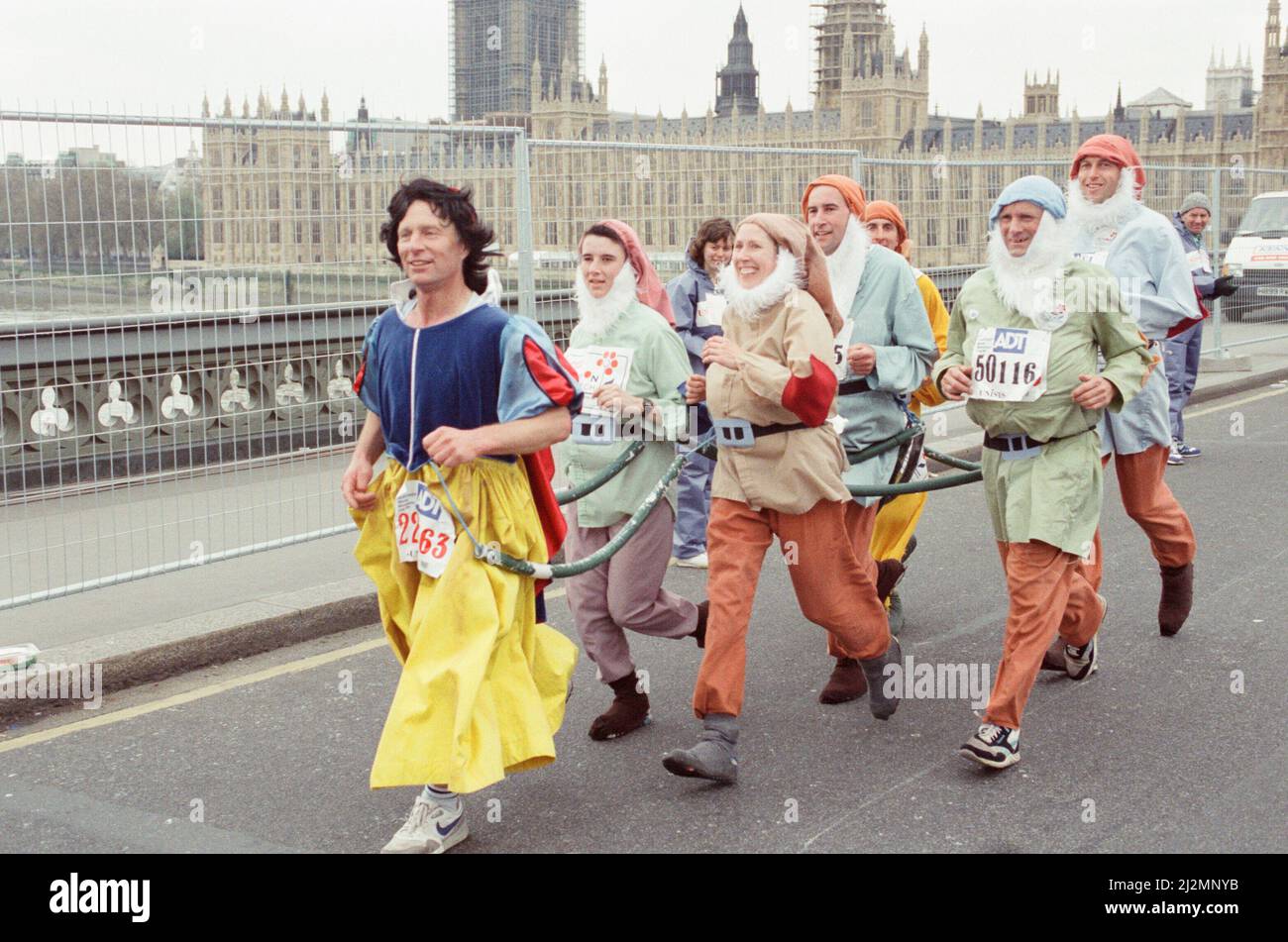 Der London Marathon - 1991Runners in ausgefallener Kleidung über Westminster Bridge, Central London. Läufer, die als Schneewittchen und die sieben Zwerge verkleidet sind. Lauf Funnies. Bild aufgenommen am 21.. April 1991 Stockfoto