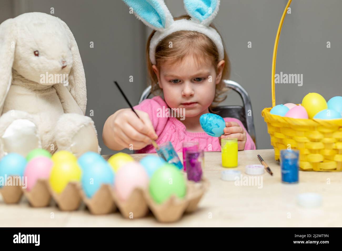 Kleines Mädchen malen Ostereier. Kind trägt Osterhasen Ohren. Vorbereitung und Dekoration für den Urlaub. Stockfoto