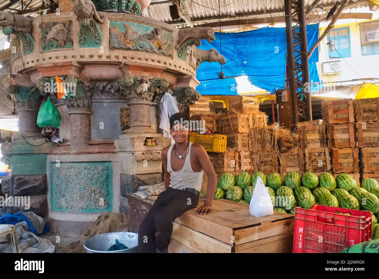 Ein Junge verkauft Wassermelonen neben einem nicht mehr existierenden Brunnen, der von John Lockwood Kipling, Vater von Rudyard Kipling, Crawford Market, Mumbai, Indien, entworfen wurde Stockfoto