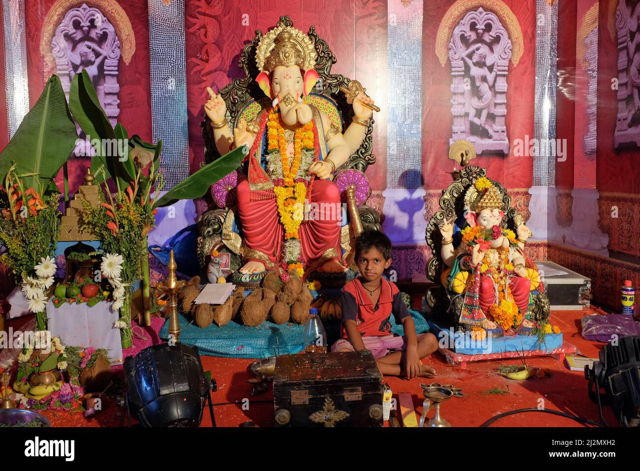 Ein indischer Junge sitzt in einem provisorischen Pavillon unter Ganesh-Figuren, die für das Festival Ganesh Chaturthi, das wichtigste Festival in Mumbai, Indien, eingerichtet wurden Stockfoto