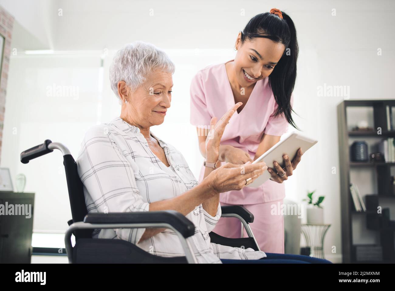 Nicht schrumpfen, um in Kind passen, lassen Sie sie ersticken. Aufnahme einer jungen Krankenschwester, die Informationen von ihrem digitalen Tablet mit einer älteren Frau im Rollstuhl teilt. Stockfoto