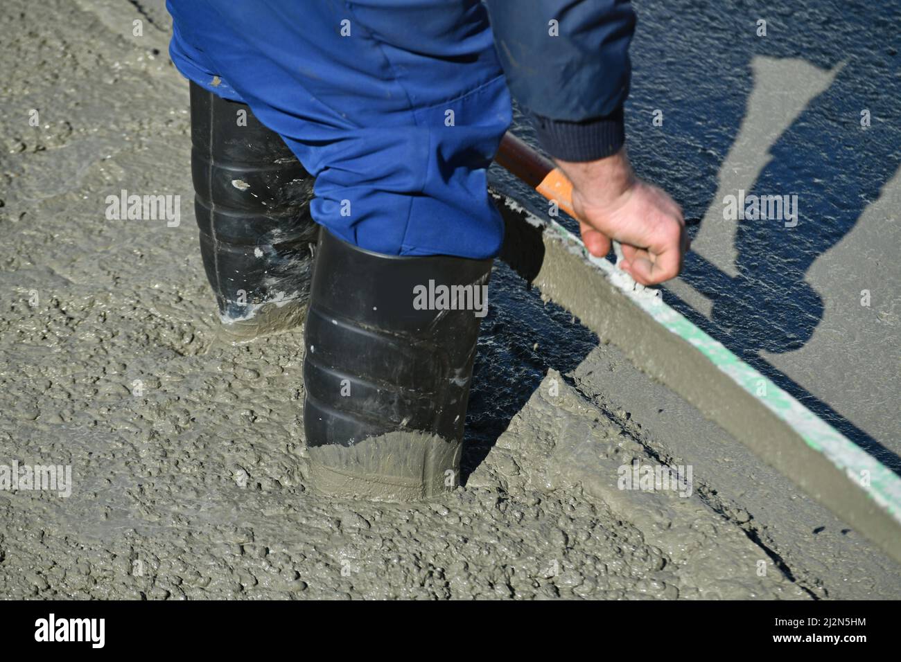 Ein Baumeister steht knöcheltief in nassem Zement während eines Betongießens Stockfoto