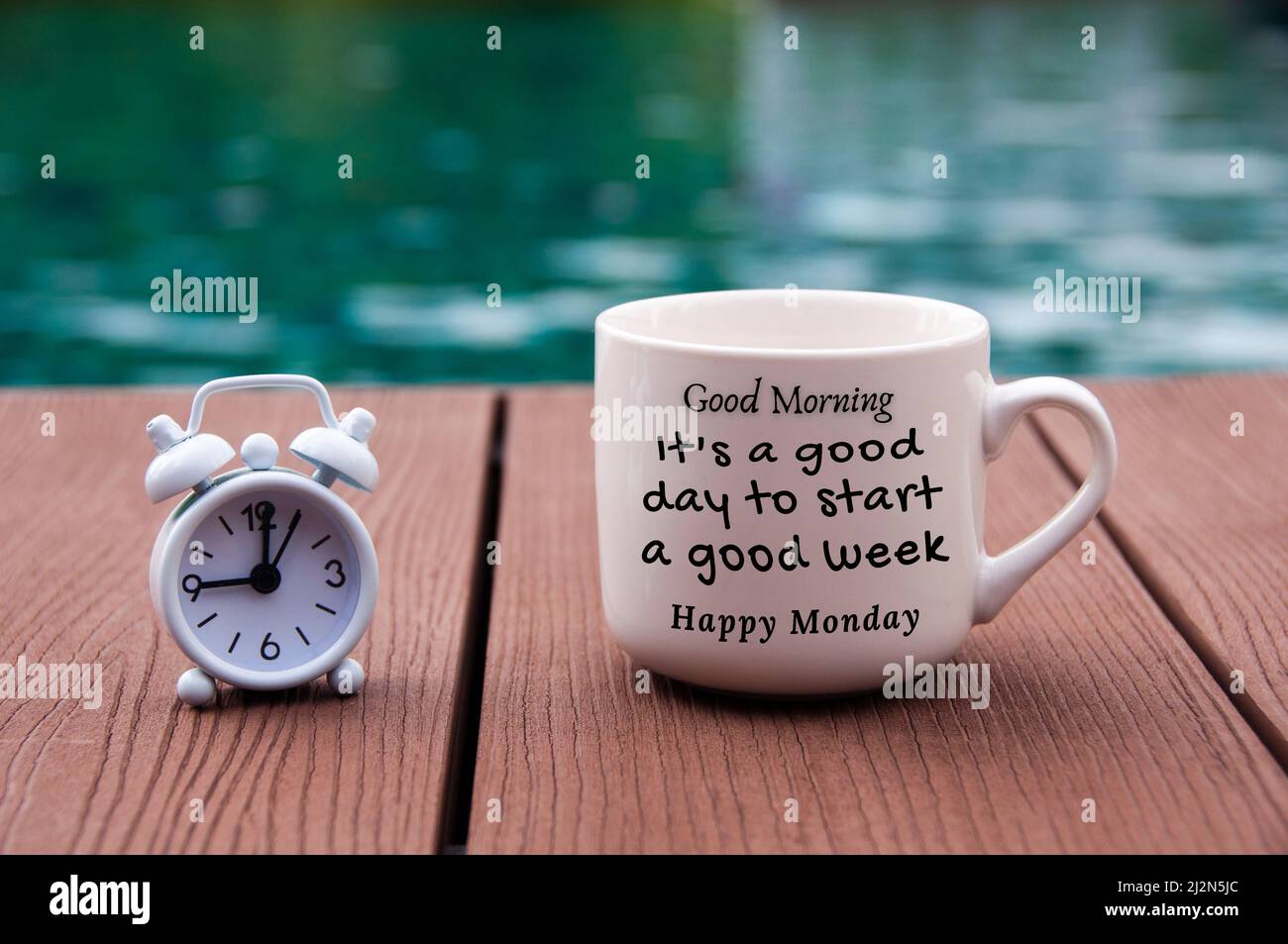 Weißer Wecker auf Holzboden mit Zitat-Text am Morgen auf Kaffeetasse - Es  ist ein guter Tag, um eine gute Woche zu beginnen. Mit verschwommenem Pool  Hintergrund Stockfotografie - Alamy